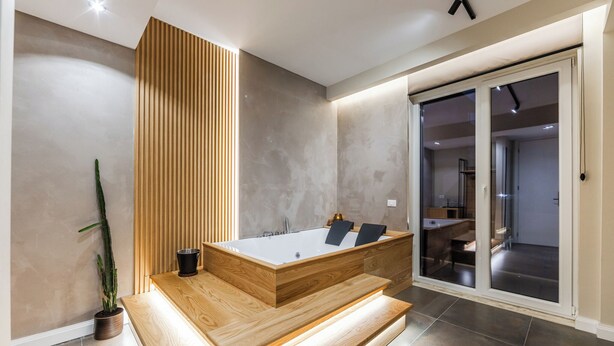 A modern bathroom with a freestanding bathtub, wooden paneling, and a potted plant. - Zoe's Villa by PS (Durrës)