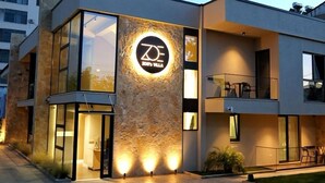 A modern building with a prominent logo on the facade, large windows, and a well-lit entrance. - Zoe's Villa by PS (Durrës)