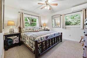 A bedroom with a bed, nightstands, a ceiling fan, windows, and a mirror. - Goldilocks! Whittier Cabin w/ Private Hot Tub! (Whittier)