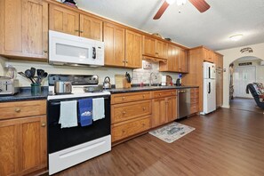 A kitchen with wooden cabinets, a microwave, stove, and a refrigerator. - Goldilocks! Whittier Cabin w/ Private Hot Tub! (Whittier)