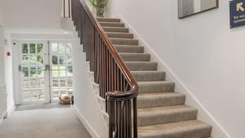 A staircase with a wooden handrail leading to a door with glass panels.