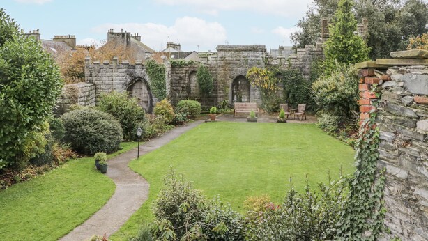 A courtyard with stone walls, a lawn, and a pathway. - Derwent (Ulverston)