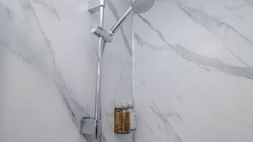 A modern shower with a handheld showerhead and a fixed showerhead, mounted on a wall with a marble pattern.