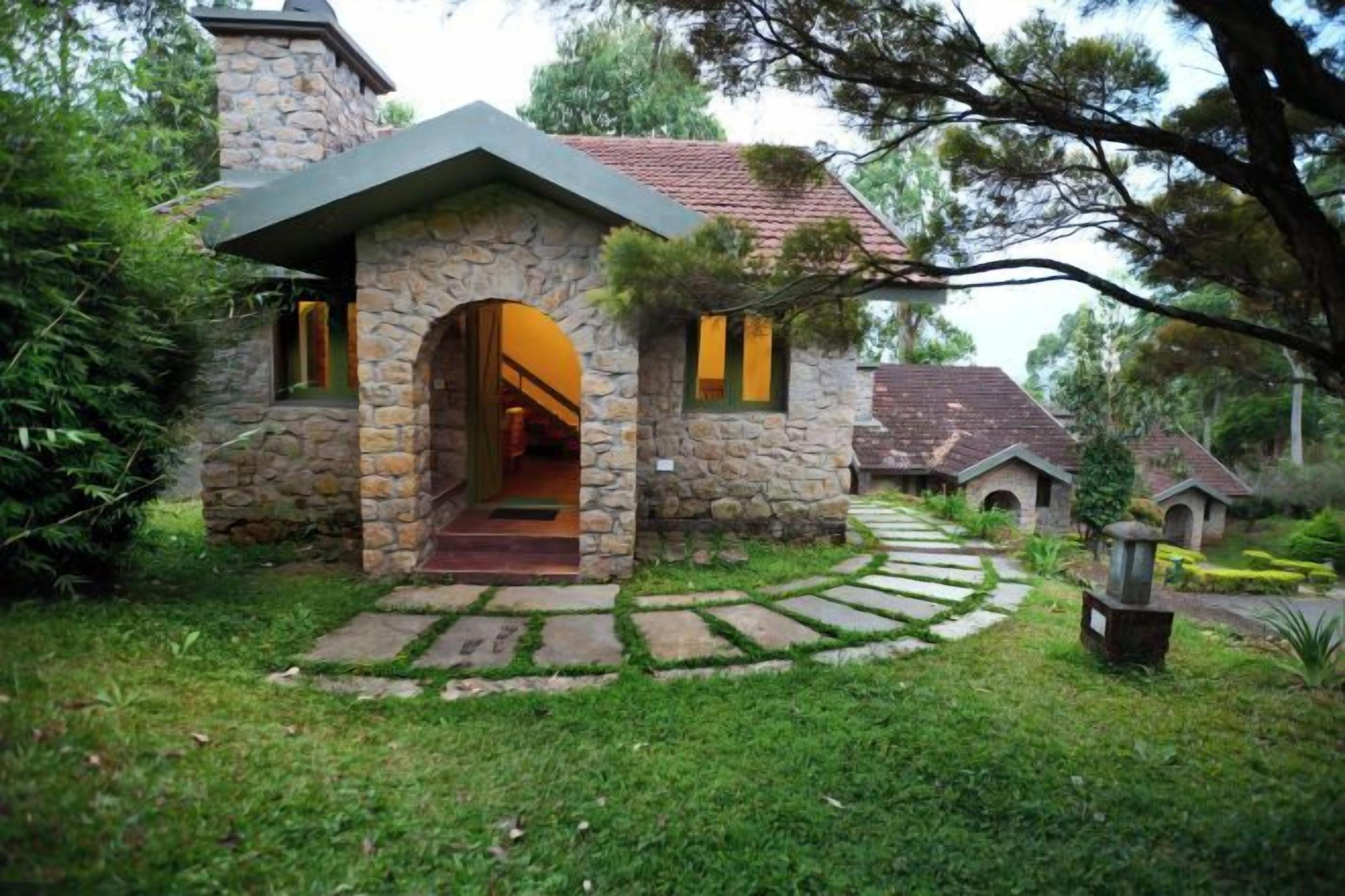 A stone house with a stone archway entrance, a pathway leading to it, and a small garden area.