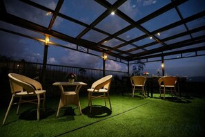 An outdoor patio with artificial grass, wicker furniture, and a pergola structure. - Mountain Club Resort (Chinnakanal)