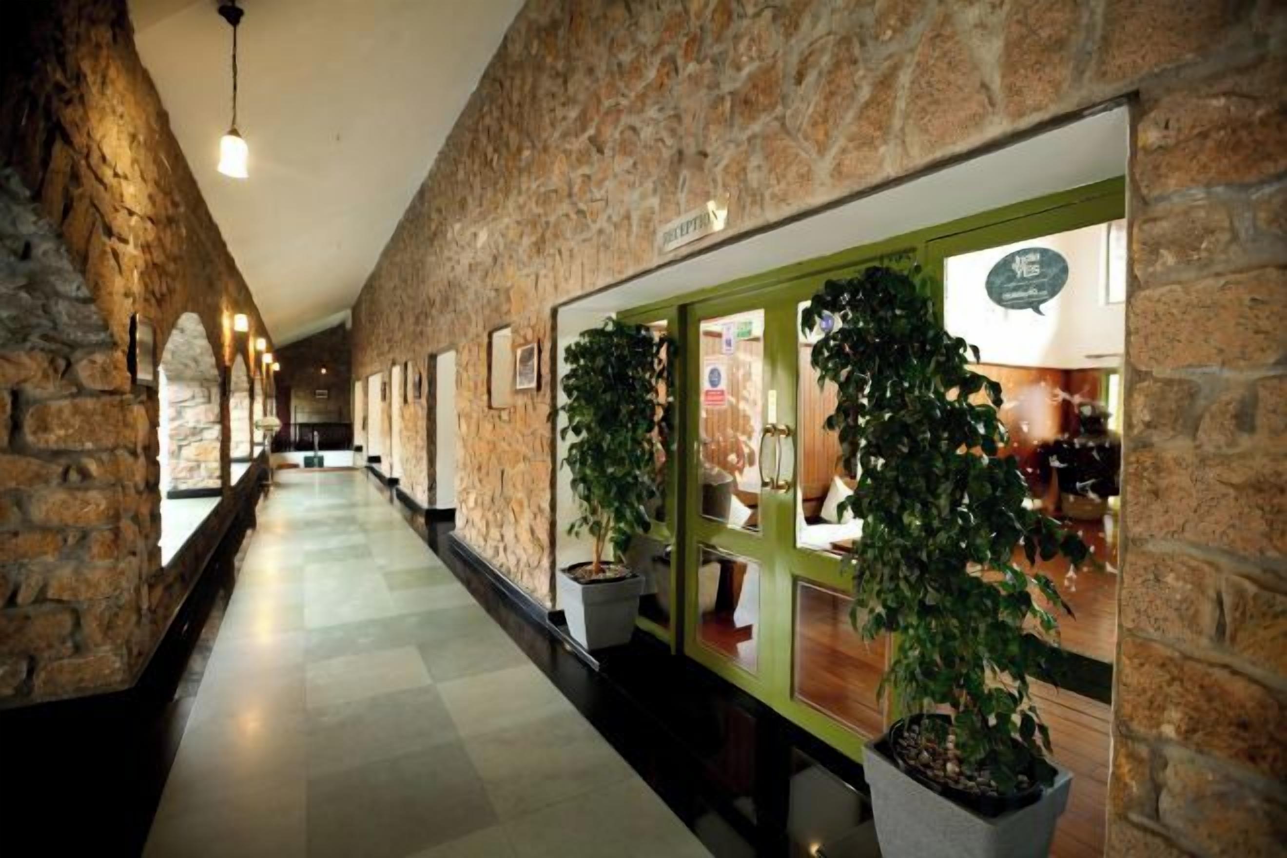 A corridor with stone walls, potted plants, and a sign indicating a restaurant.