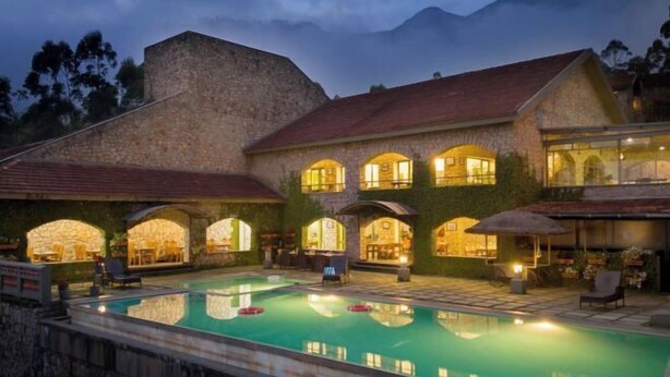 A stone building with a swimming pool, arched windows, and outdoor seating areas. - Mountain Club Resort (Chinnakanal)