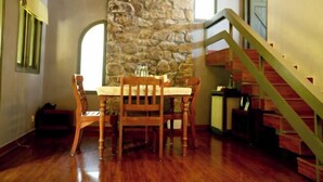 A dining area with a stone wall, wooden table, and chairs. - Mountain Club Resort (Chinnakanal)