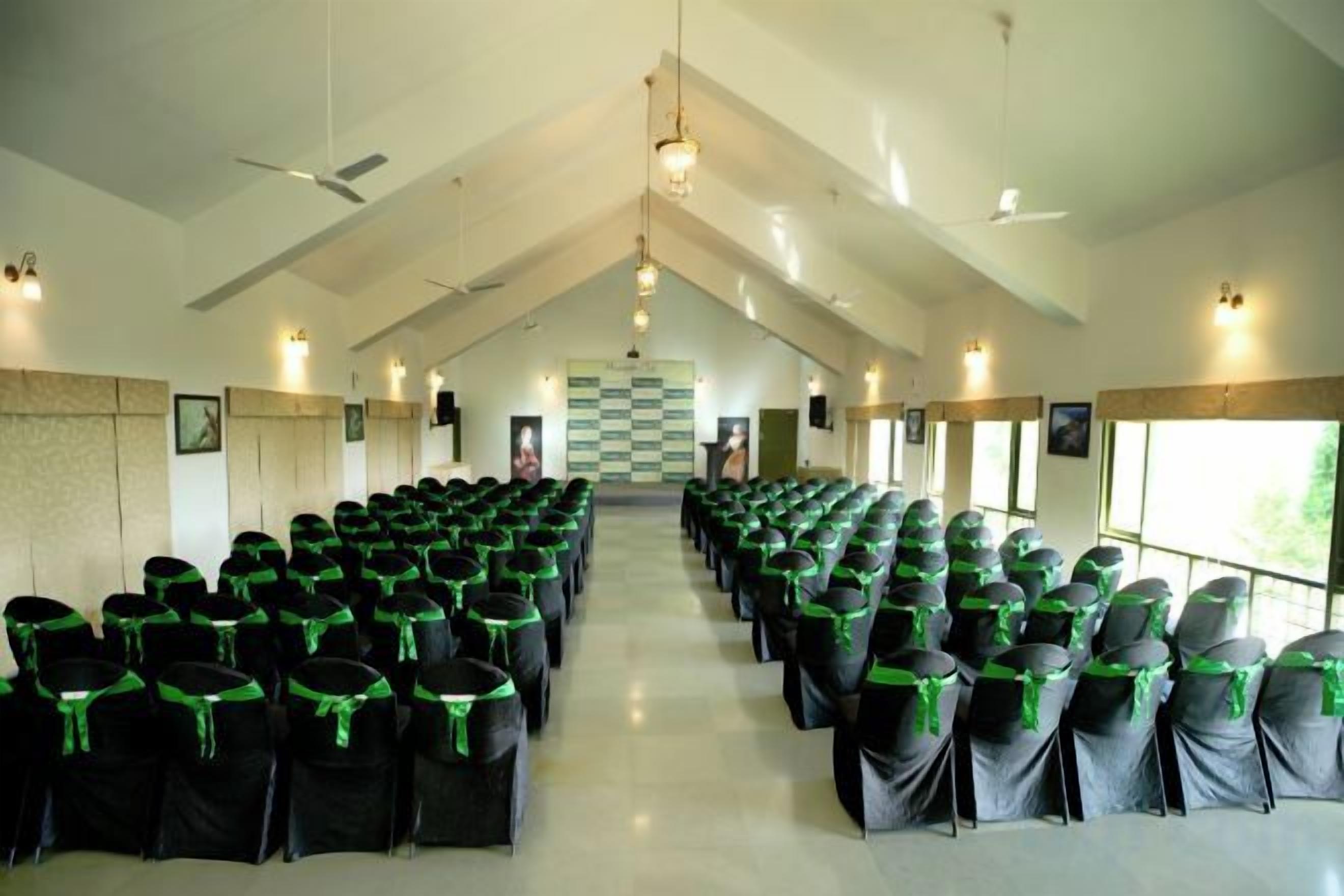 A large hall with rows of chairs, a high ceiling, and a checkered floor pattern.