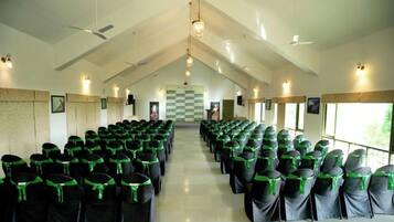 A large hall with rows of chairs, a high ceiling, and a checkered floor pattern.