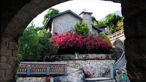 A stone building with a staircase leading up to it, surrounded by greenery and pink flowers. - Mountain Club Resort (Chinnakanal)