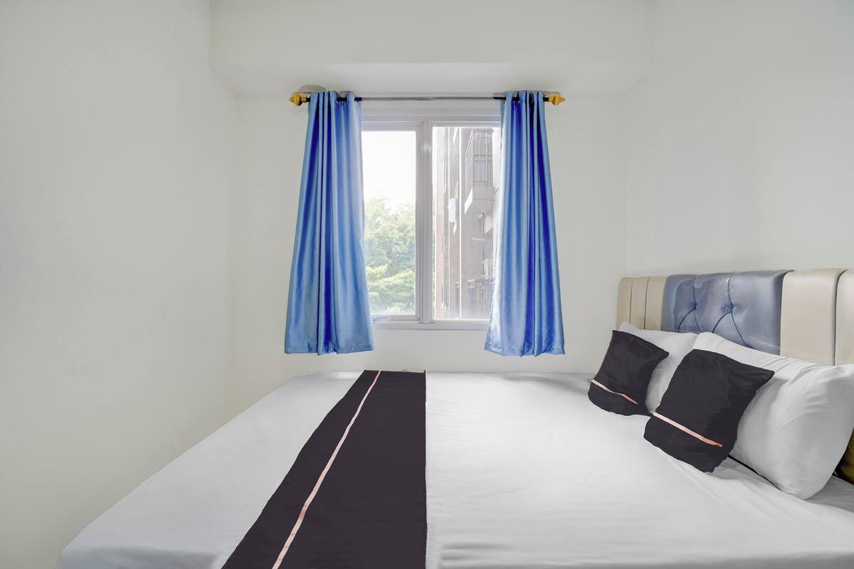 A neatly made bed with a black and white striped bed runner, a headboard with a tufted design, and two pillows.