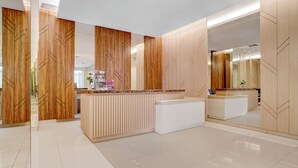 Een moderne receptie met houten lambrisering en een wit receptiebalie.