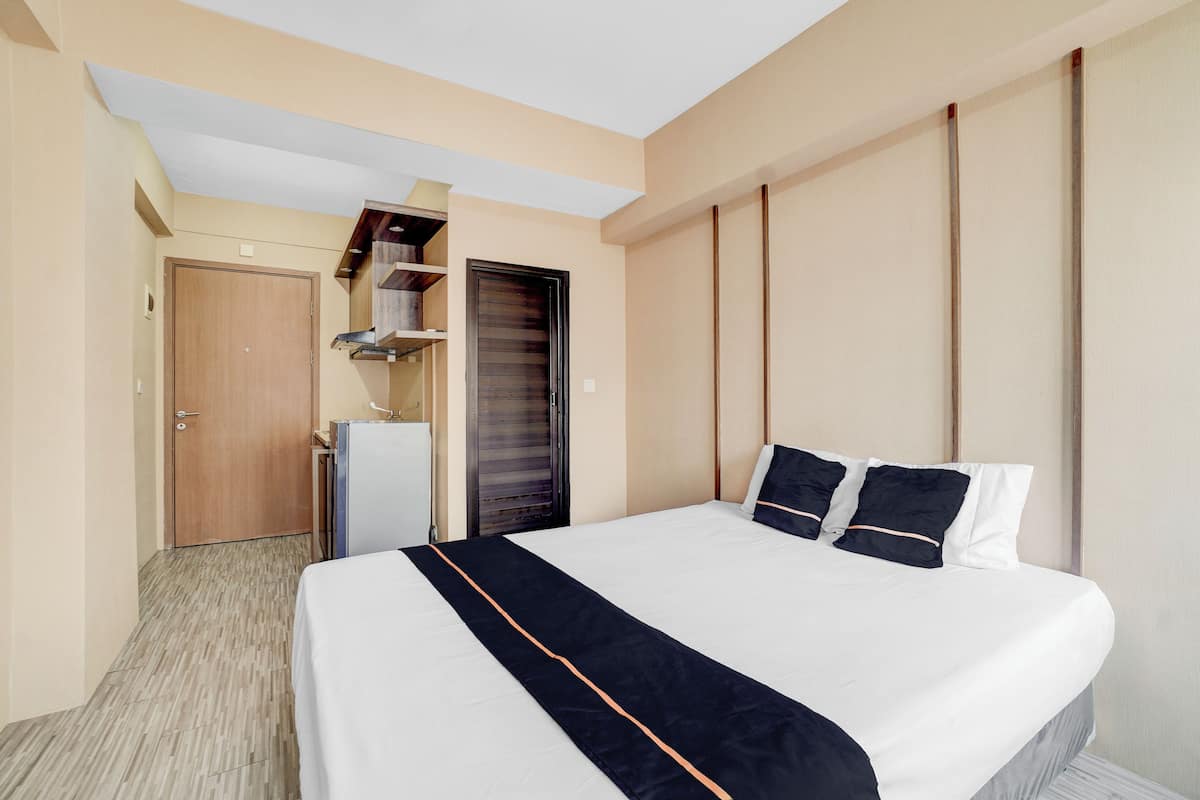 A hotel room with a large bed, a wardrobe, a desk, and a door leading to a balcony.