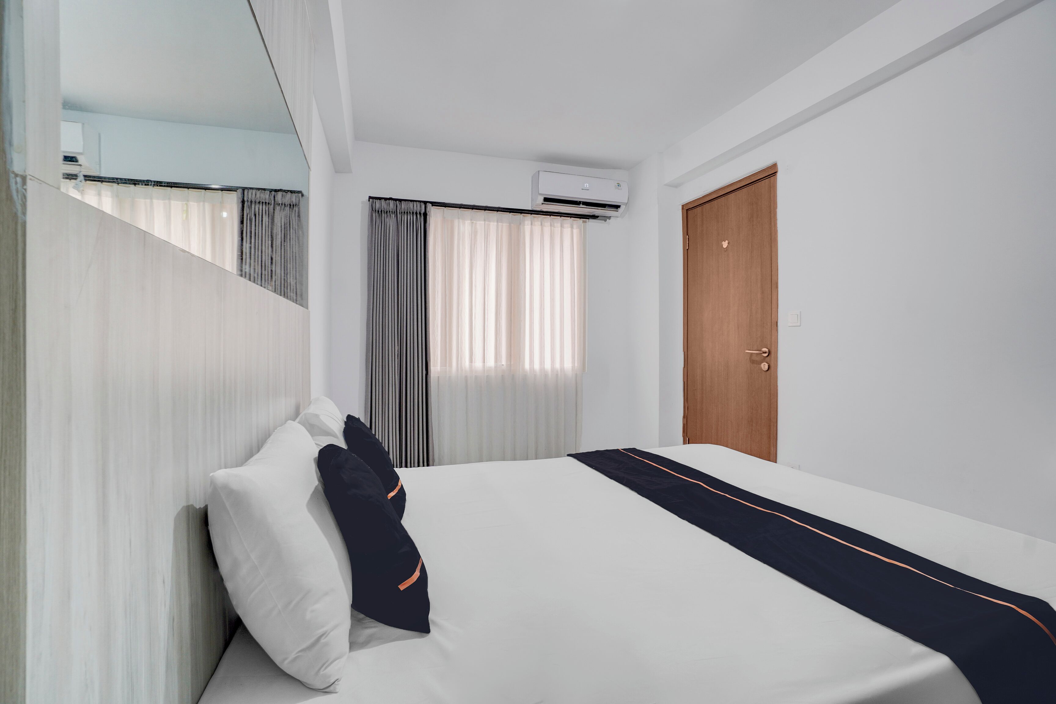 Una habitación de hotel con una cama, una puerta de madera y un equipo de aire acondicionado.