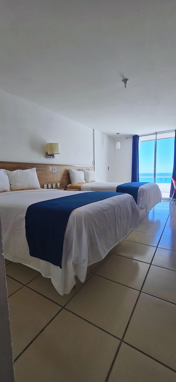 A hotel room with two beds, a large window with a view, and a ceiling fan. - Hotel Playamar (Mazatlán)