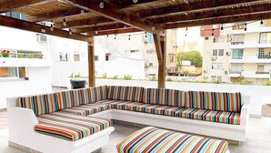 A modern outdoor seating area with a white sofa and ottoman, featuring colorful striped cushions. - Hotel Playamar (Mazatlán)