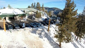 A snow-covered parking lot with cars and a building with a green roof. - Ring in 2026 in South Lake Tahoe in a large, cozy 2 bedroom suite (Stateline)