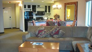 A living room with a sofa, two coffee tables, and a kitchen in the background. - Ring in 2026 in South Lake Tahoe in a large, cozy 2 bedroom suite (Stateline)