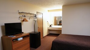 A hotel room with a TV, a small fridge, a wooden dresser, a mirror, and two beds. - Hill Street Inn (Osmond)