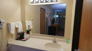 A bathroom with a large mirror, a sink, and a hairdryer. - Hill Street Inn (Osmond)