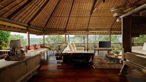 A spacious, open-air lounge with a high thatched roof, wooden furniture, and a view of greenery outside. - Villa Inka Ubud by Nakula (Bali)