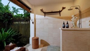 A modern bathroom with a shower, a vanity with toiletries, and a decorative shelf. - Villa Inka Ubud by Nakula (Bali)