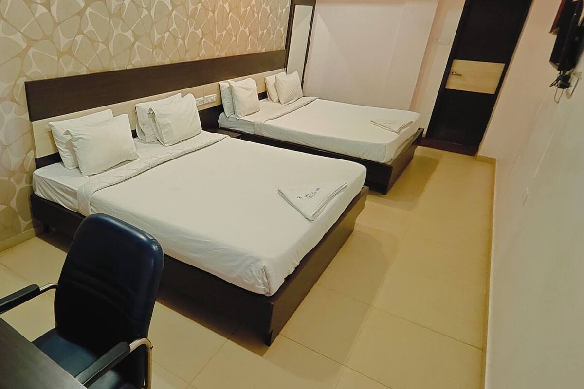 Ein Hotelzimmer mit zwei Einzelbetten, einem Schreibtisch mit Stuhl und einem kleinen Tisch mit Telefon.