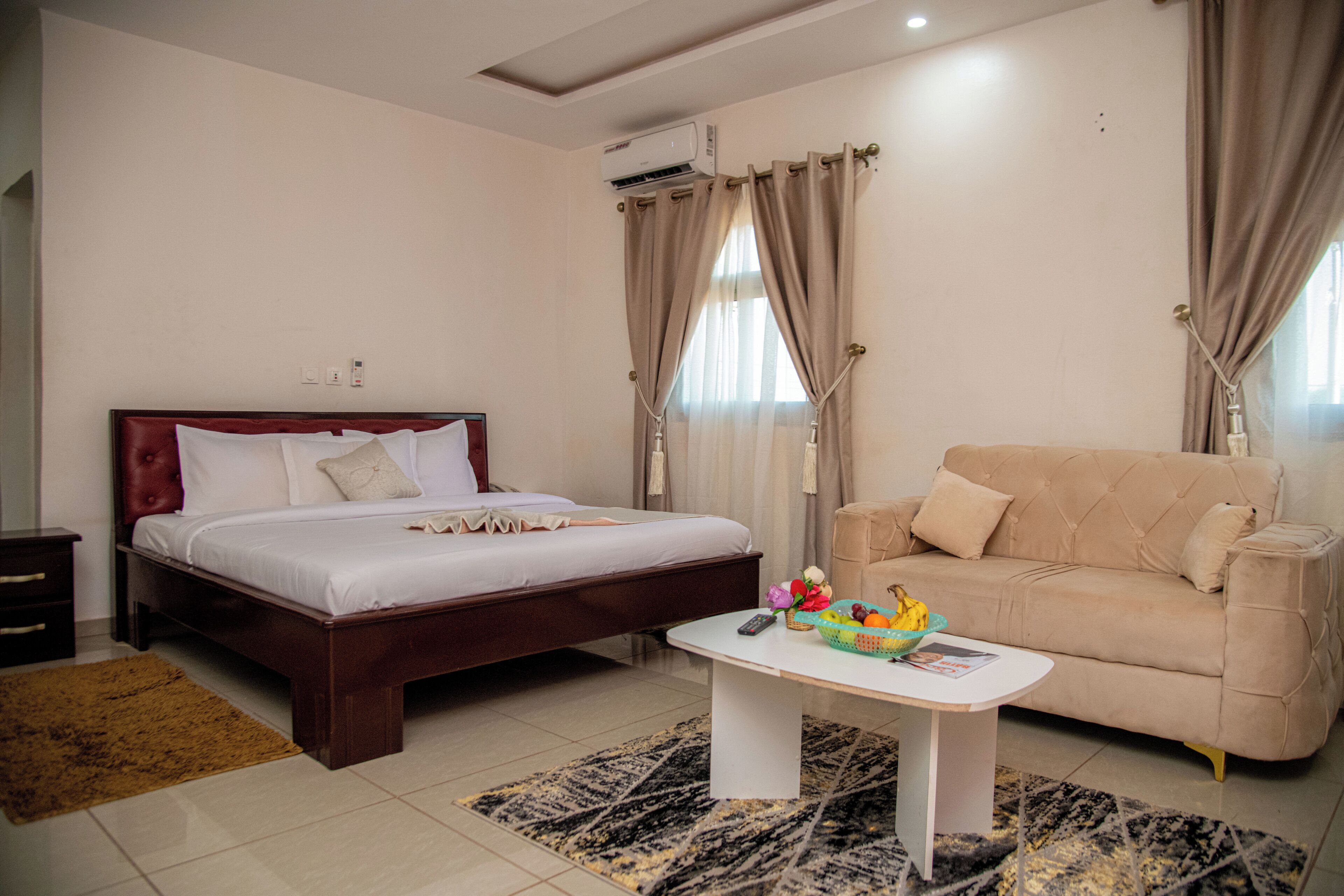 Una habitación de hotel con una cama, un sofá, una mesa de centro y un aire acondicionado.