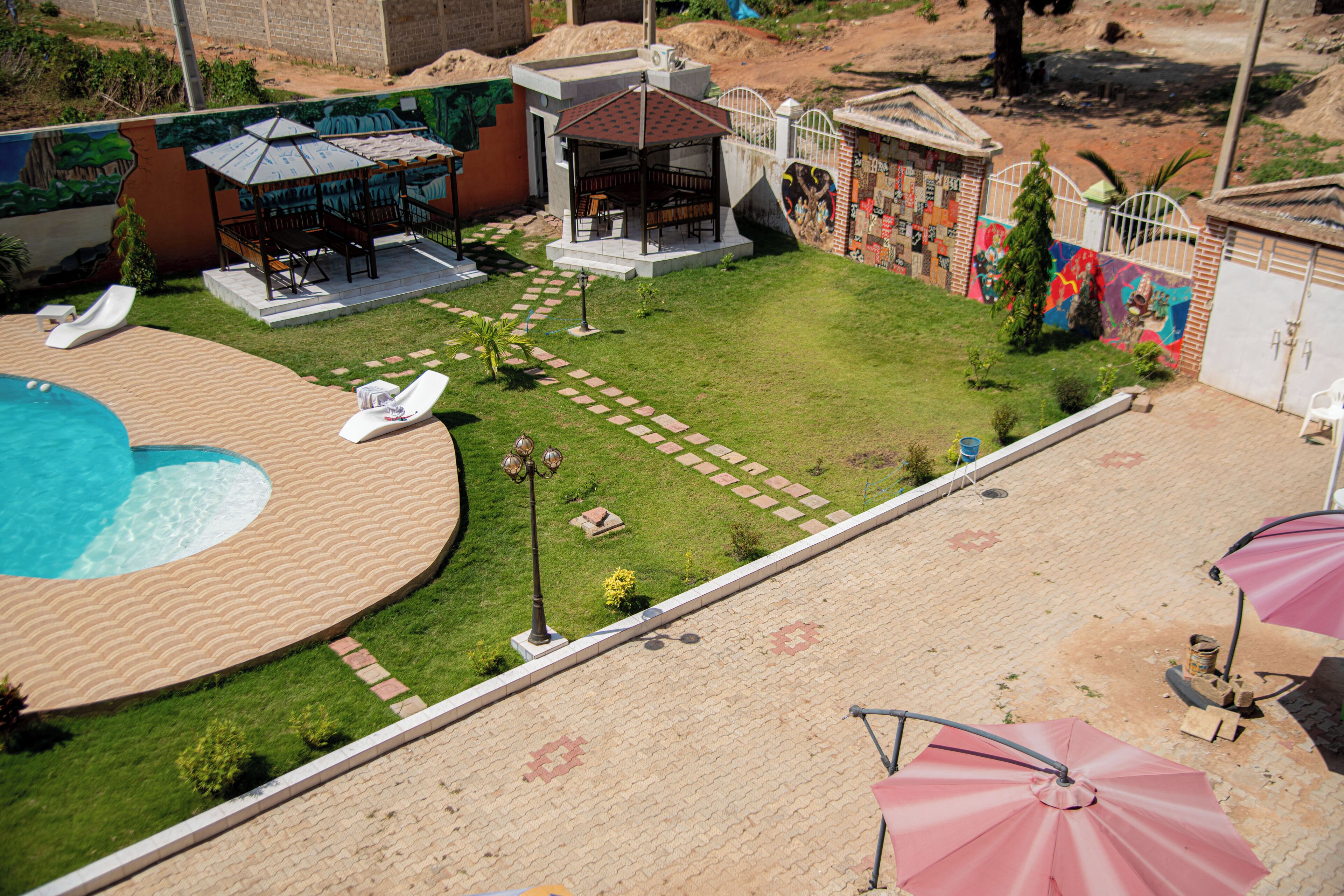 A pool area with lounge chairs, a gazebo, and a patio with umbrellas.