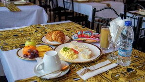 Ein Tisch reichhaltig gedeckt mit Frühstücksleckereien, darunter Croissants, Obst, Rührei, Toast und Saft.