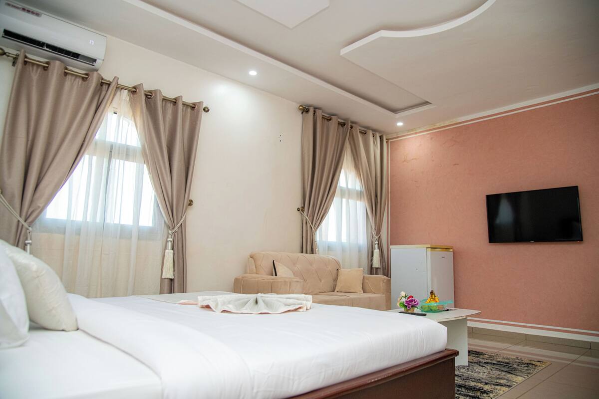 A hotel room with a bed, a sofa, a TV, and a desk.