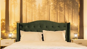 A bedroom with a large bed, green upholstered headboard, white bedding, and a forest-themed wall tapestry. There are two bedside tables with lamps. - Grand Chalet Ramina Poiana Brasov (Brașov)