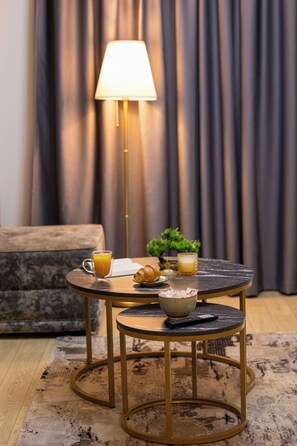 Et rundt bord med en lampe, en skål, en croissant og et glas appelsinjuice.