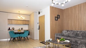 A modern living room with a grey sofa, teal chairs, and a round coffee table. - Grand Chalet Ramina Poiana Brasov (Brașov)