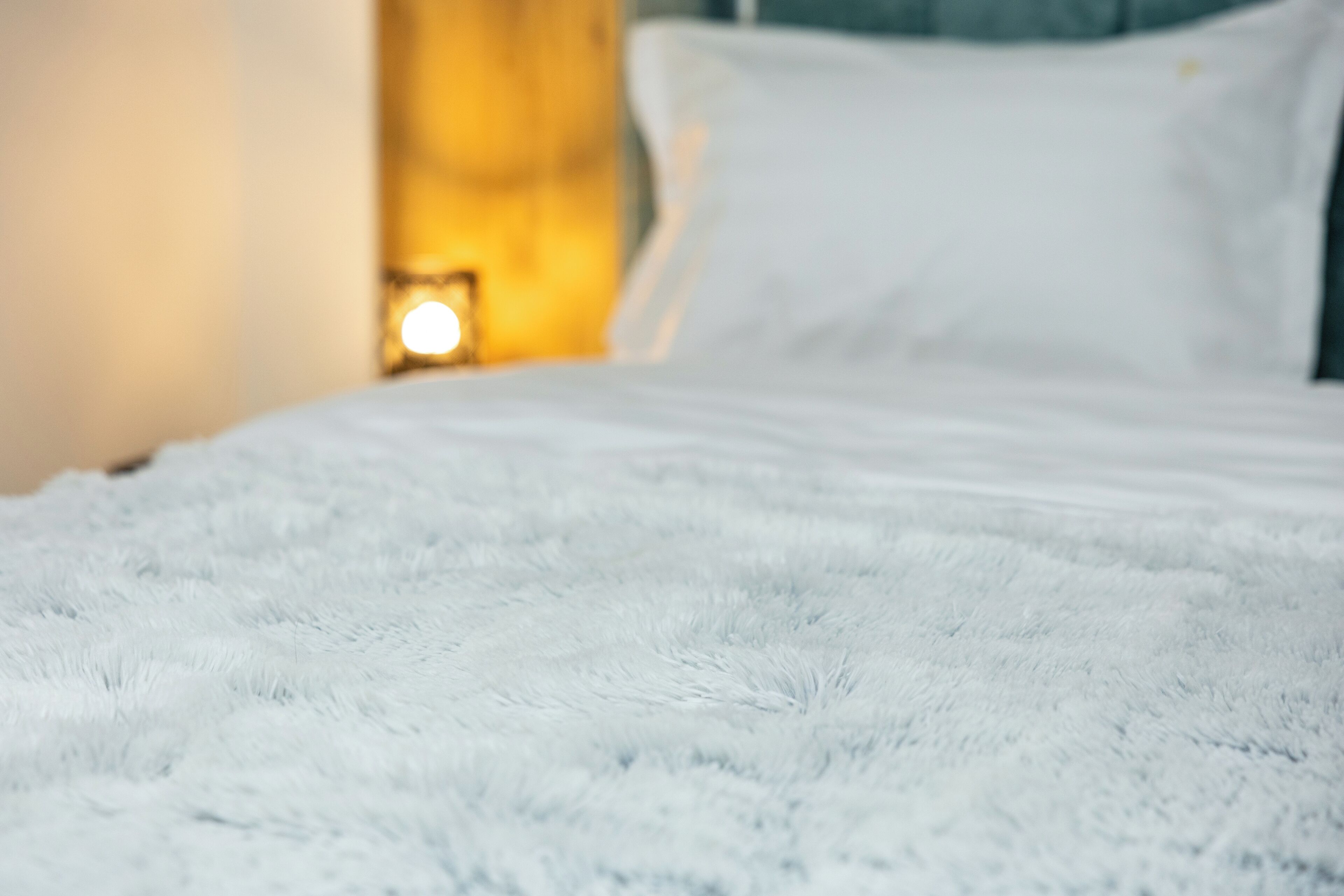 A bed with a fluffy white cover.
