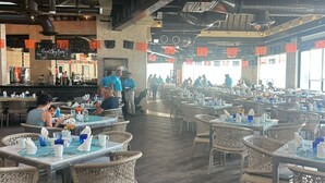 A spacious restaurant with high ceilings, exposed beams, and wicker chairs. Tables are set with blue and white tableware. - Deluxe Ocean View Suite – The Ultimate Luxury Experience in Cancún (Cancún)