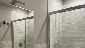 Een moderne badkamer met een wit wastafelmeubel, spiegel en een douchecabine van glas.