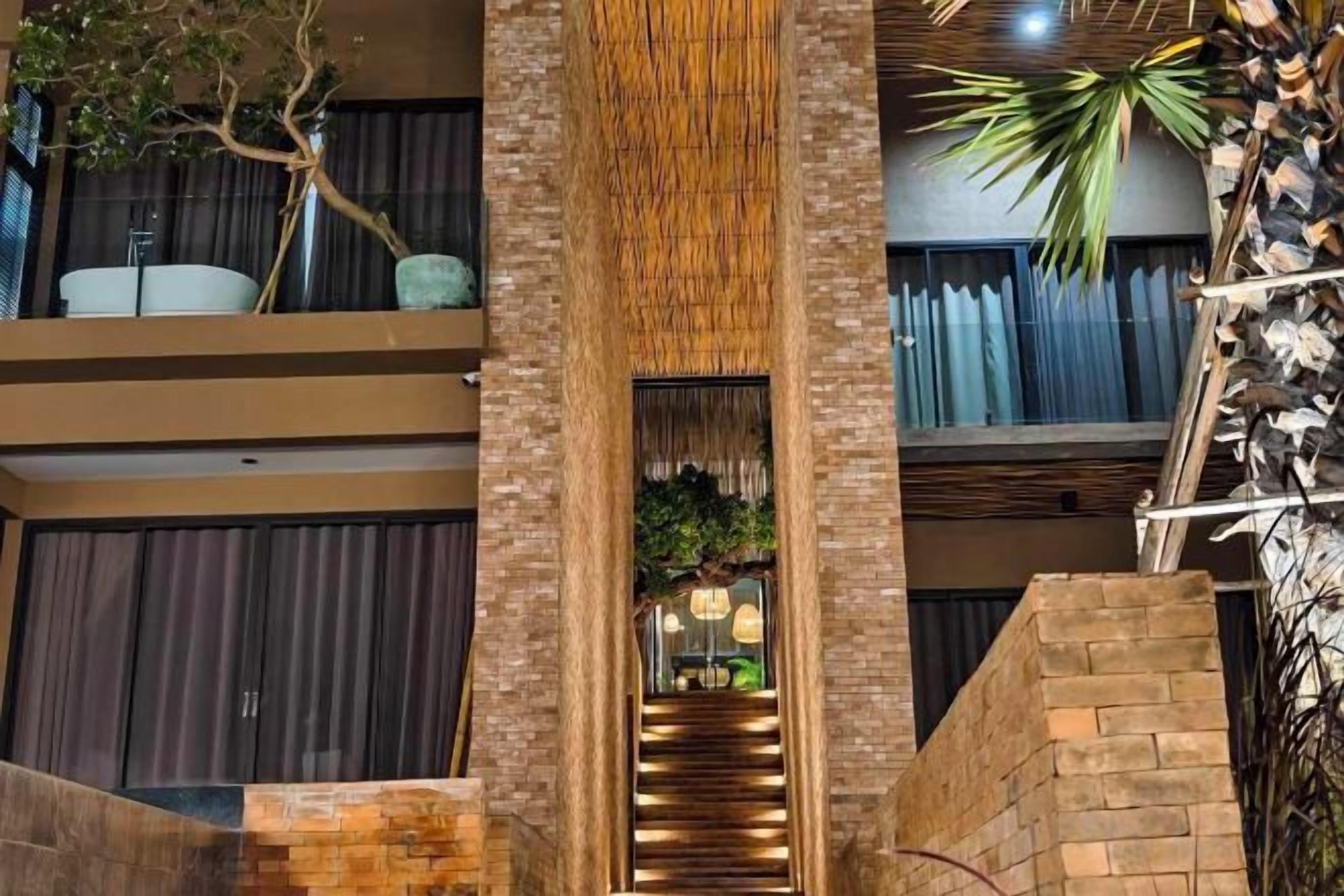 Un interior de varios niveles con una escalera central, una planta y vista al piso superior.