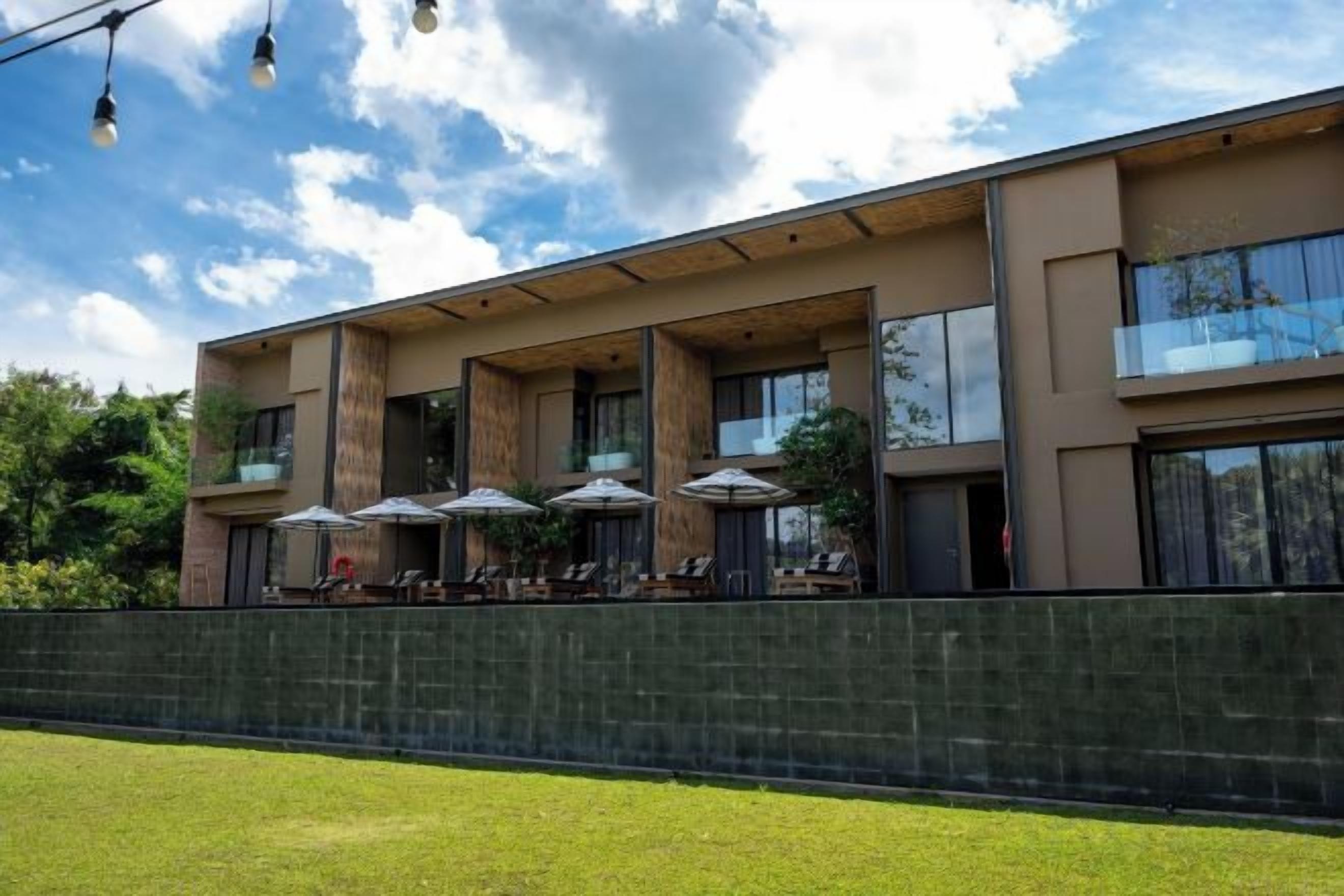 Un edificio moderno con mesas al aire libre y un muro de piedra.