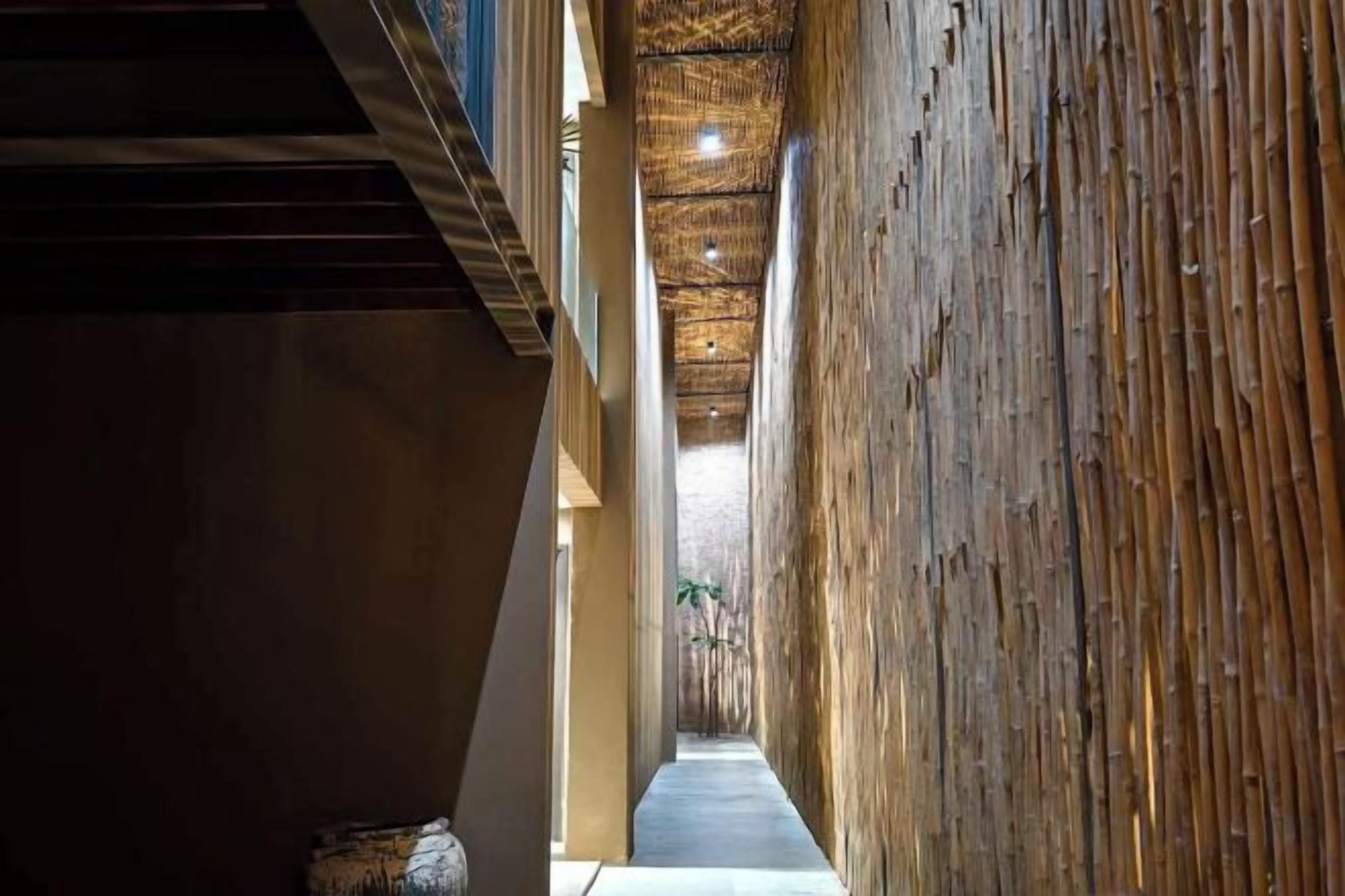 A corridor with a wooden wall and a ceiling with a woven pattern.
