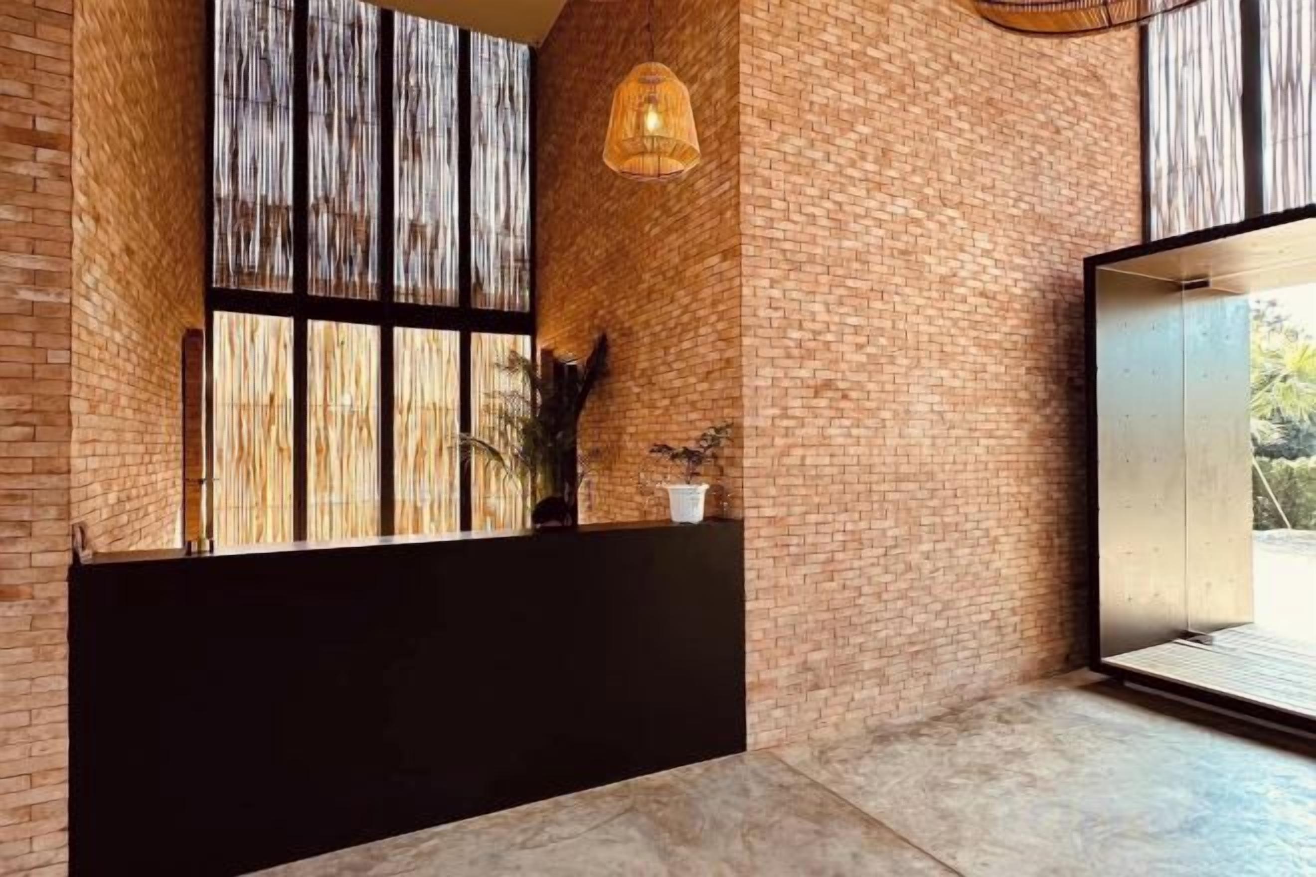A reception area with a brick wall, a large window, and a black reception desk.