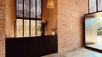A reception area with a brick wall, a large window, and a black reception desk.