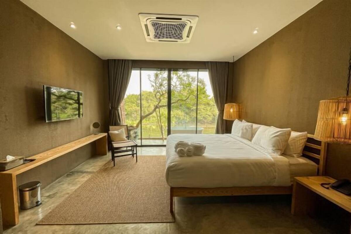 Una habitación de hotel moderna con una cama grande, un escritorio, una silla y un televisor en la pared.