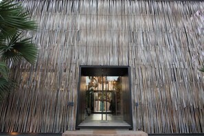 A building facade with vertical wooden slats and a central entrance. - Historykan Kanchanaburi Hotel (Kanchanaburi)