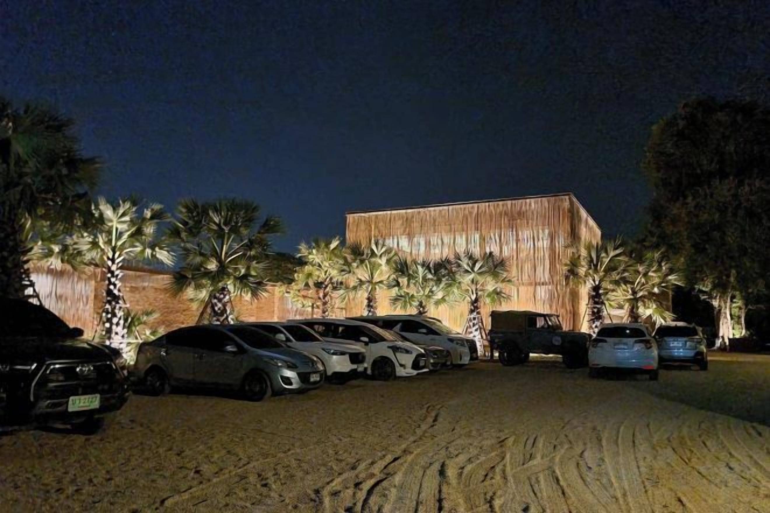 Un área de estacionamiento con varios autos y un edificio de fachada de madera.