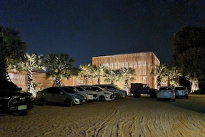 Un espace de stationnement avec plusieurs voitures et un bâtiment doté d’une façade en bois.