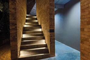 A staircase with a brick wall on one side and a plain wall on the other, leading to an upper level. - Historykan Kanchanaburi Hotel (Kanchanaburi)