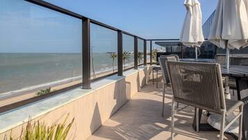 Un balcon avec vue sur l’océan, des sièges d’extérieur et des parasols.