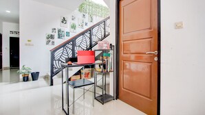 A staircase with a metal railing, a wooden door, and a shelf with various items. - Hotel O Rumah Daun Guesthouse Jogja (Yogyakarta)